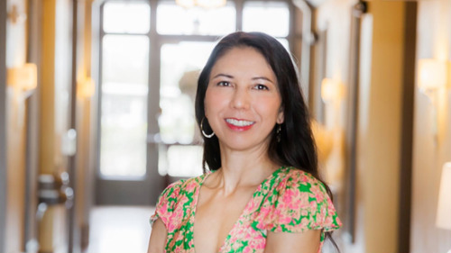 Smiling woman in floral dress standing in bright hallway discussing chronic fatigue and oral health