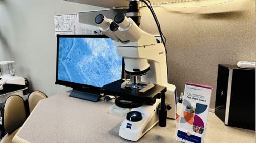 Microscope for saliva sample with attached monitor screen and pamphlet on saliva sample