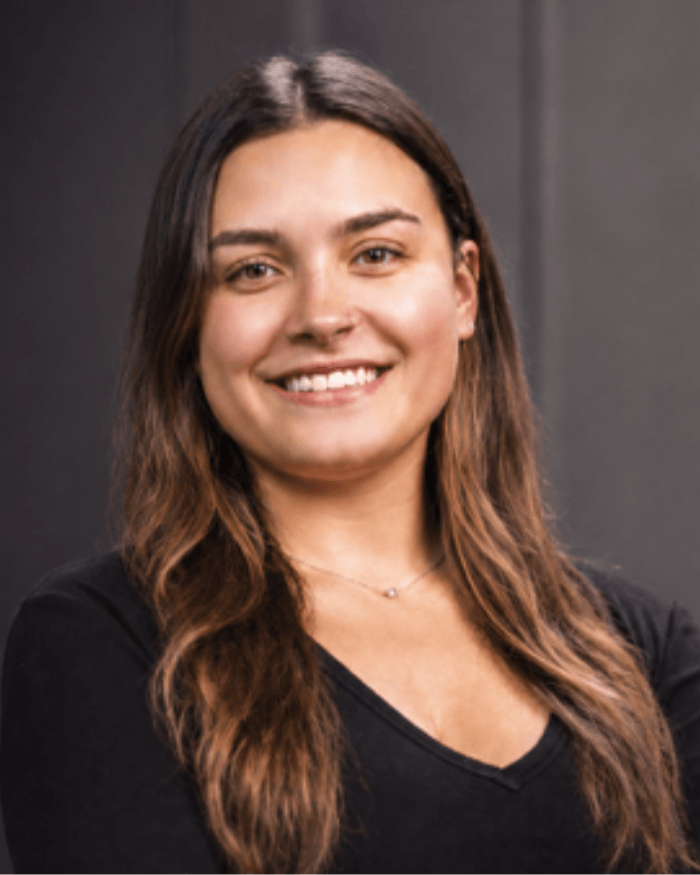 Dea, dental assistant, smiling warmly in professional black top with long brown hair